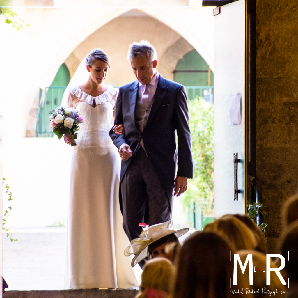 la mariée rentre aux bras de son père dans l'église sous une belle lumière et un bel éclairage sur les visages. cérémonie de la messe de mariage.