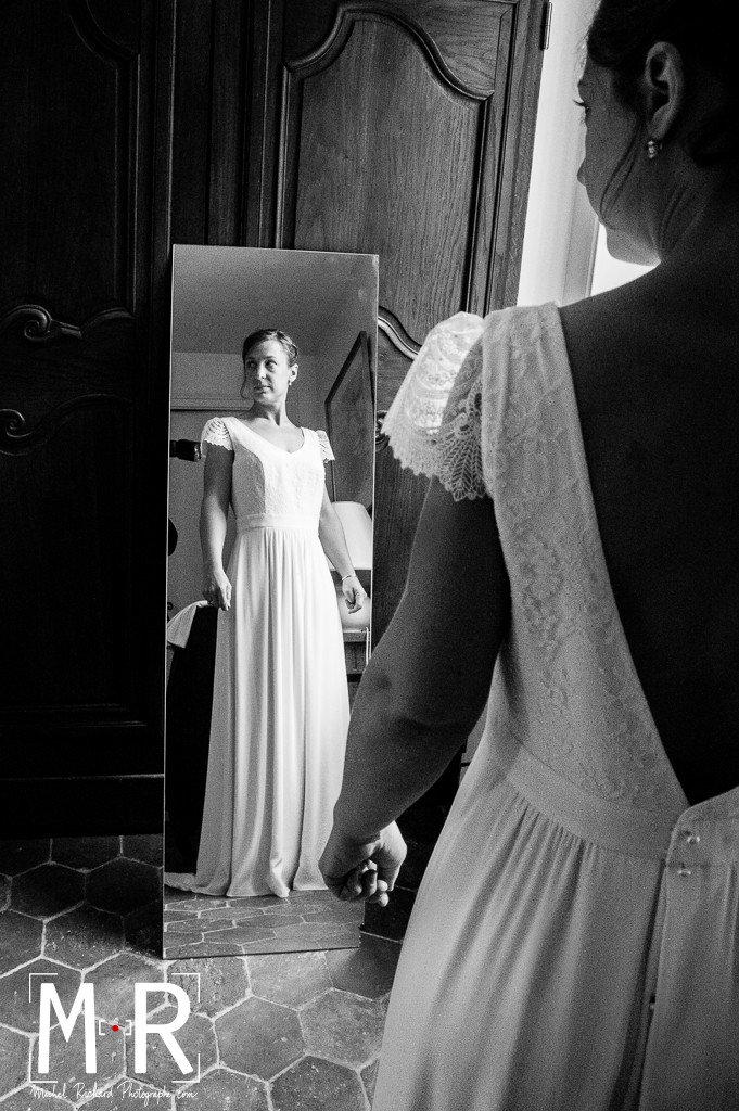 la mariée regarde sa robe dans un miroir
