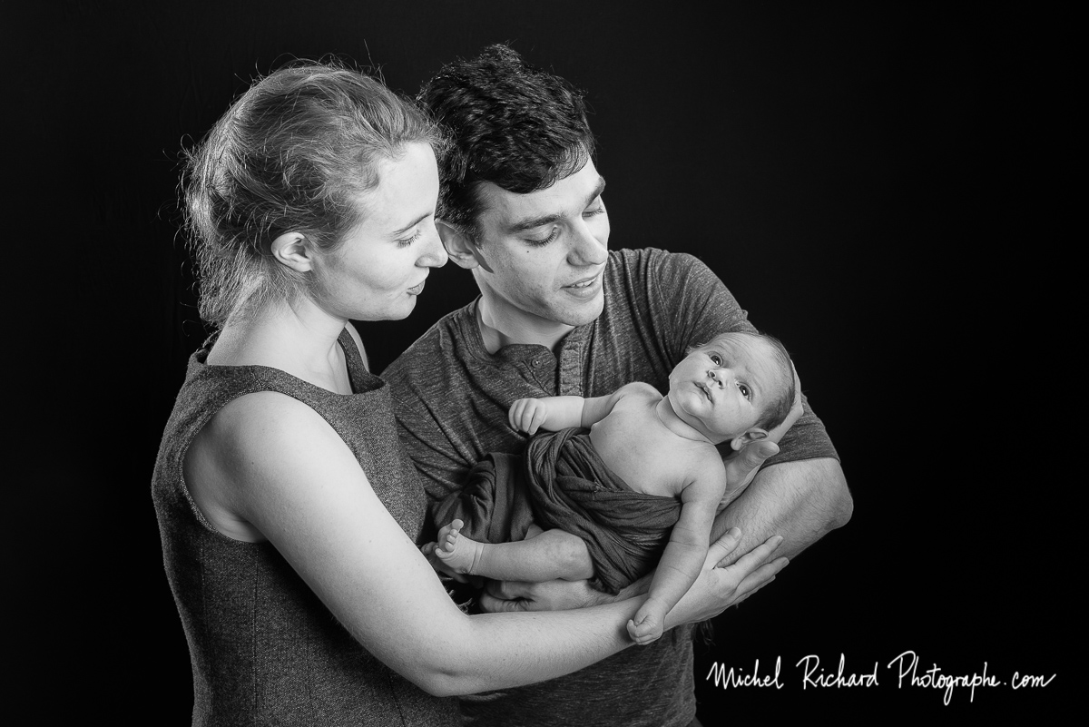 les parents tiennent le bébé nouveau-né dans leurs bras. Papa, Maman et bébé en séance studio noir et blanc