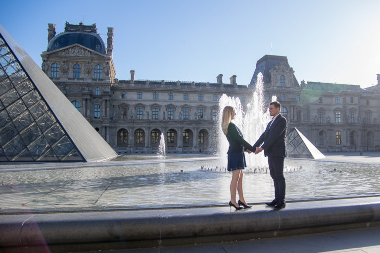 lovely couple in Paris in the Louvres with fountain and sun